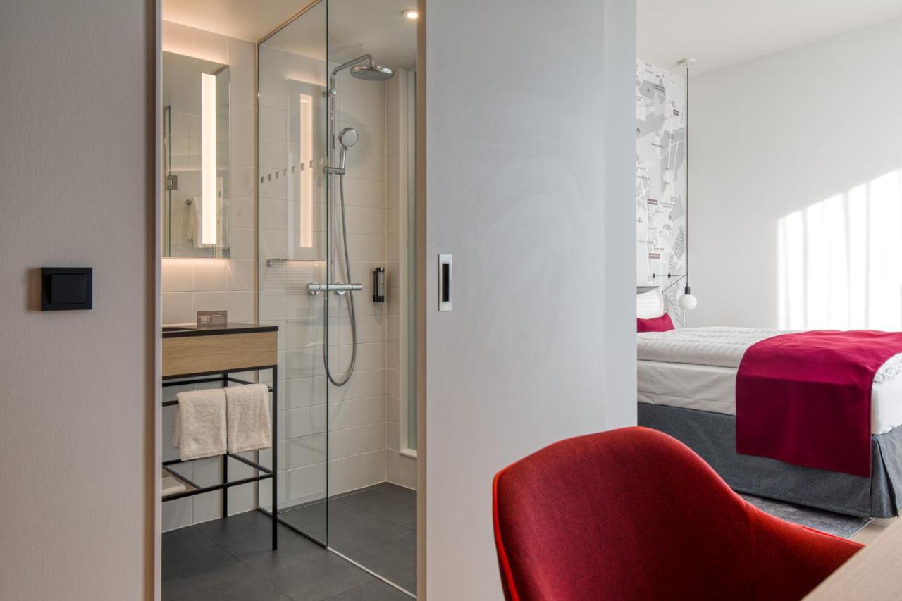 Intercityhotel Berlin Airport Ber Terminal 1 & 2 Schoenefeld Exterior photo The photo shows a modern hotel room or bathroom space. On the left, there is a glass-enclosed shower area with a sleek design, featuring a showerhead and minimalist fixtures. Adjacent to the shower, there's a sink area with a stylish countertop and a